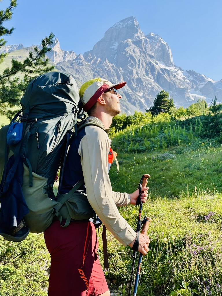 Hiker with a large backpack pausing beneath twin rock spires
