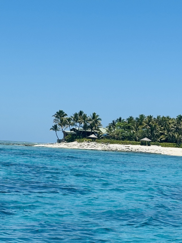 Tiny islet with a few huts ringed by clear lagoon water