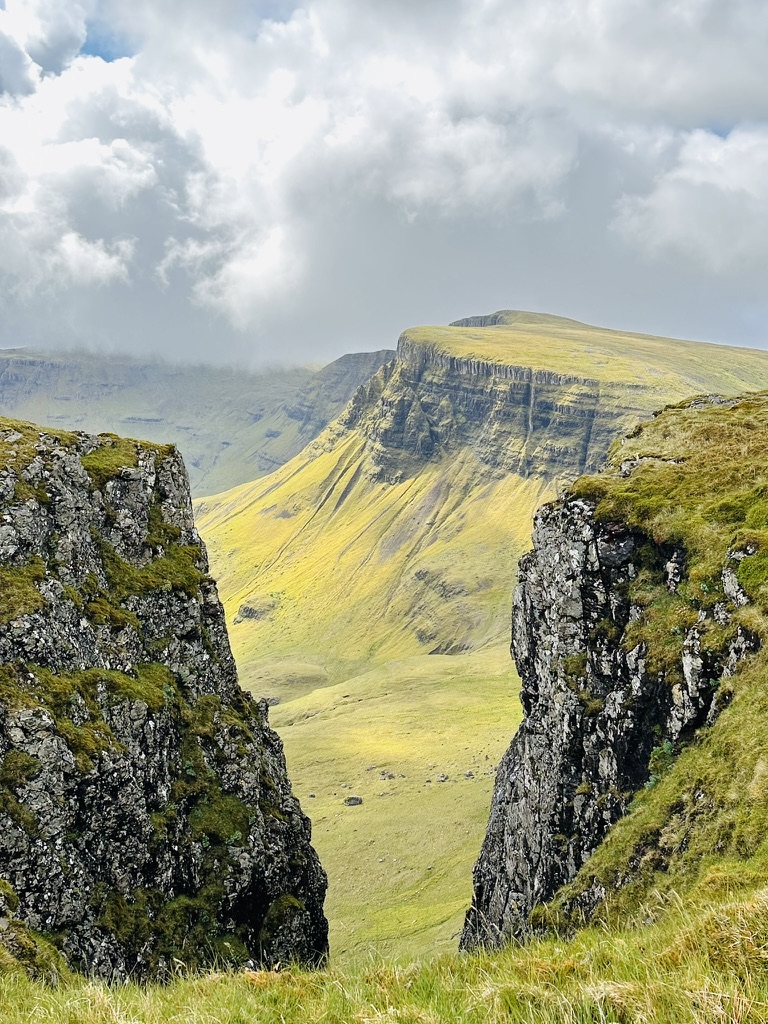Grassy ledges on sea cliffs framing a sunlit valley