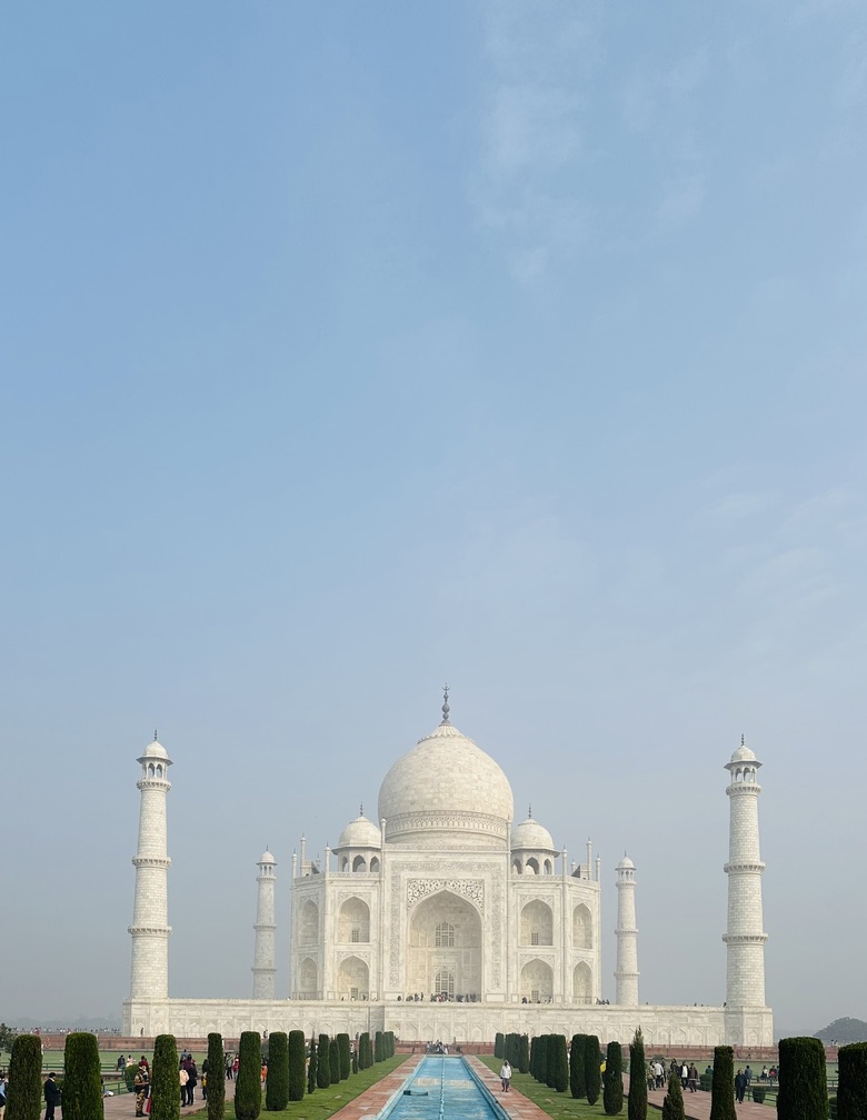 White marble mausoleum and reflecting pool beneath a pale blue sky