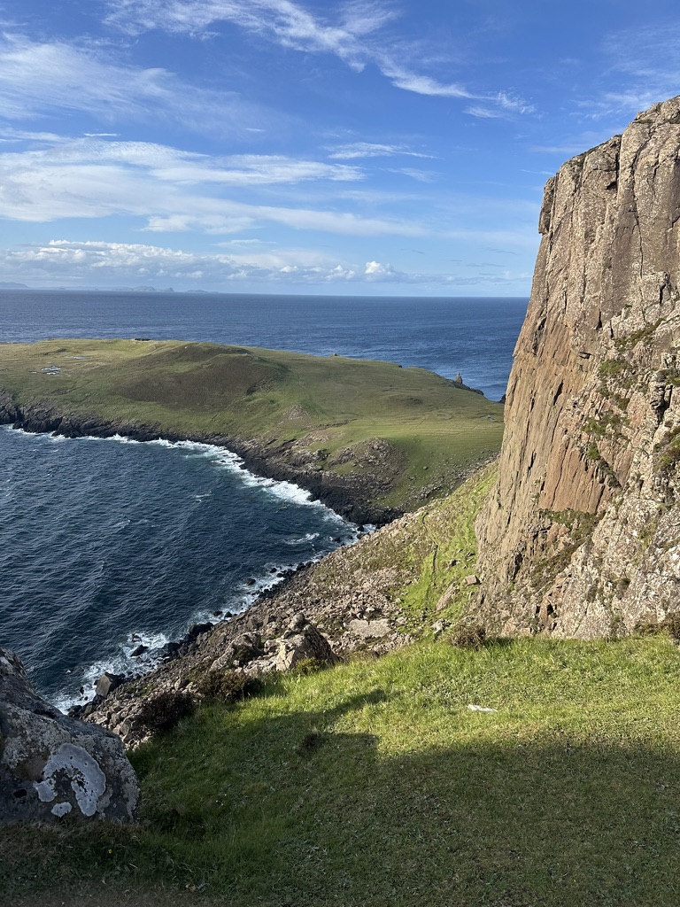 Sheer rock face and green headland above the sea