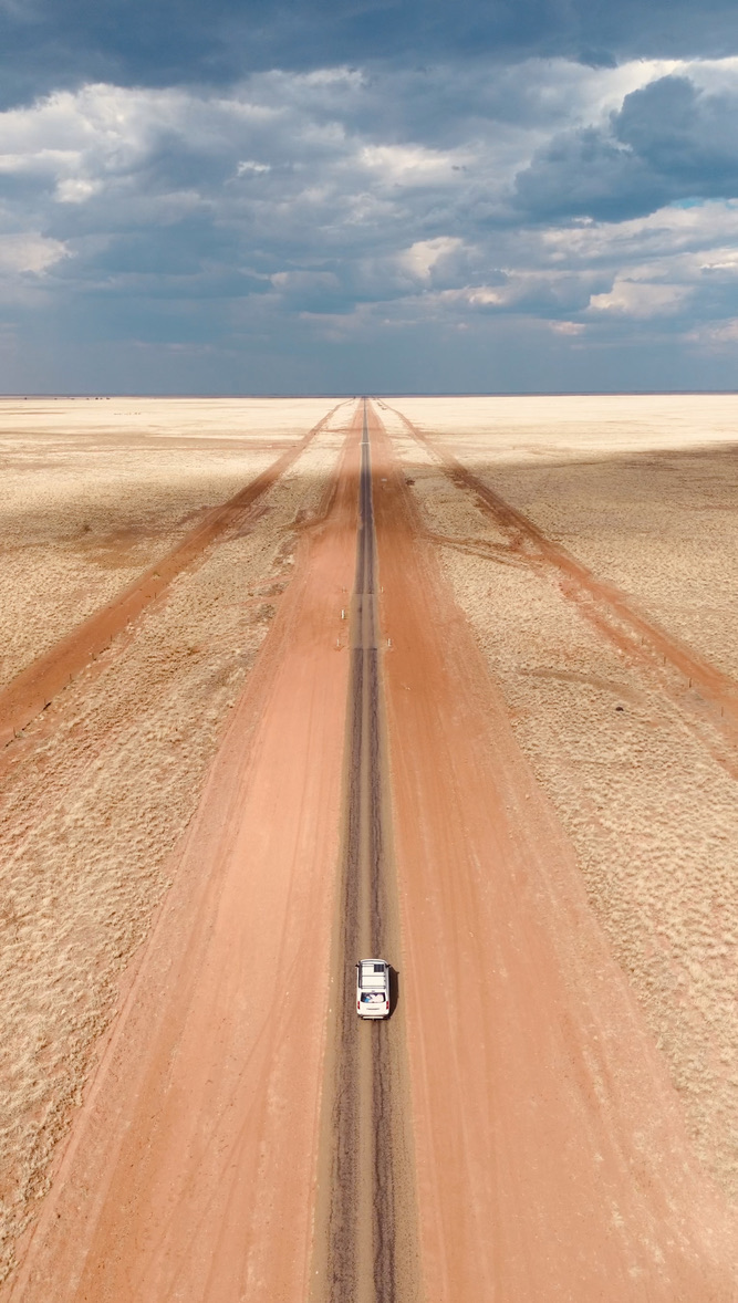 Four-wheel drive on a straight road crossing a vast Australian plain