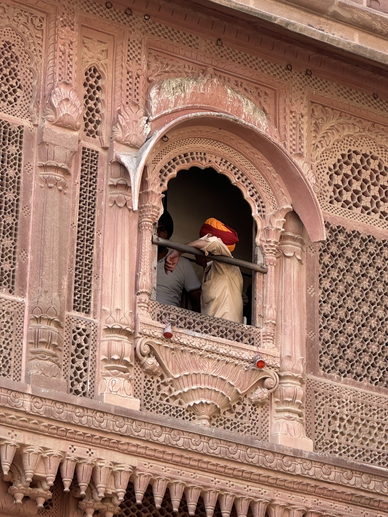 Figures framed by an intricately carved sandstone window