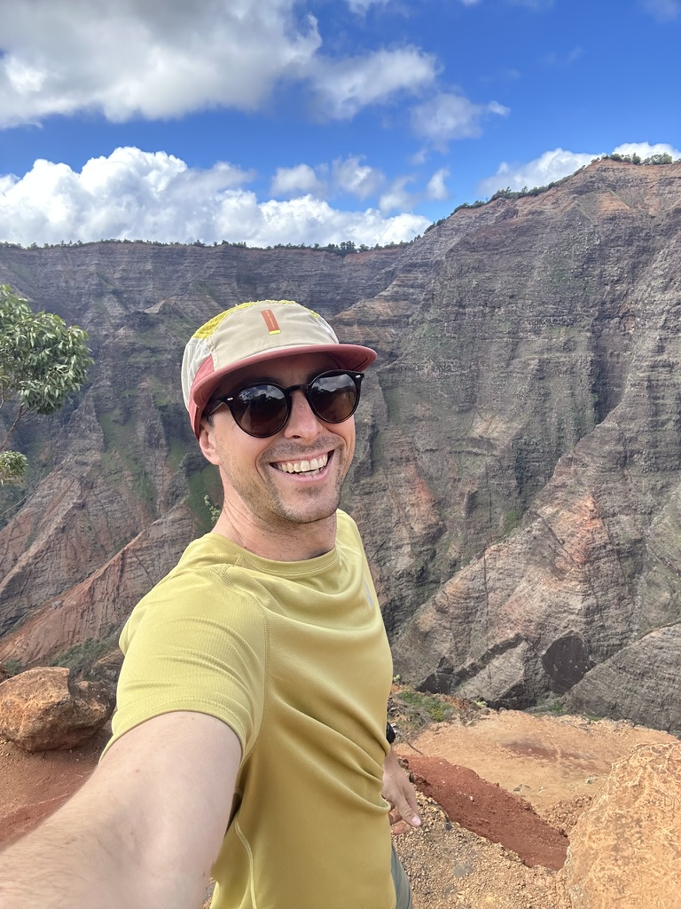 Standing at a canyon overlook with red cliffs behind