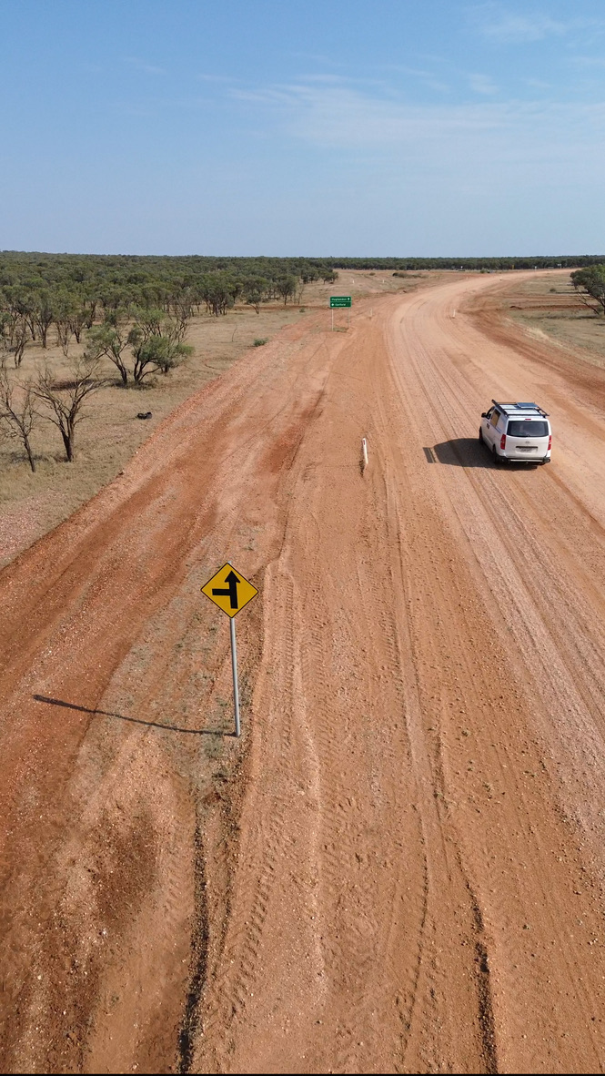 Four-wheel drive following a remote red dirt road through bushland