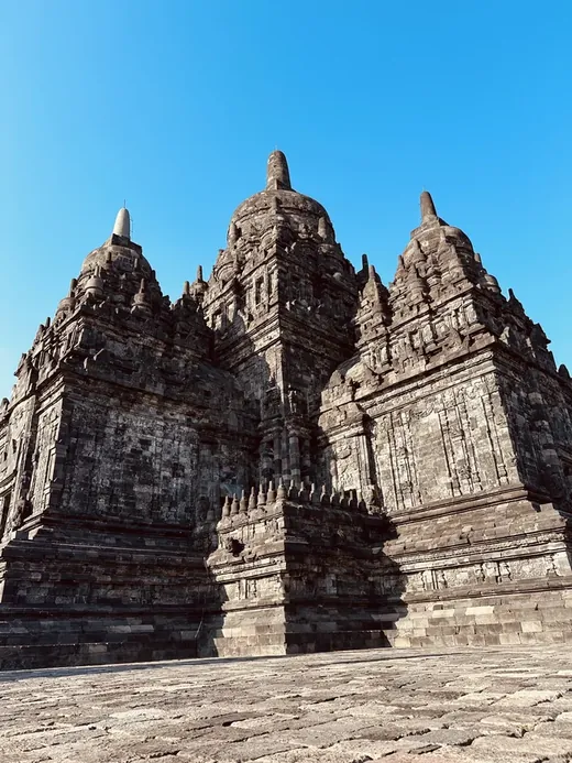 Indonesia route: a dark stone temple against a bright blue sky