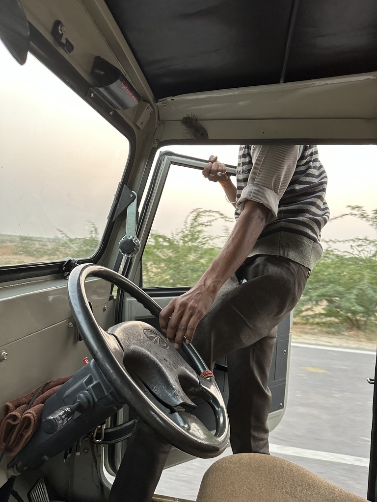 A driver steering his jeep while leaning out of the open door