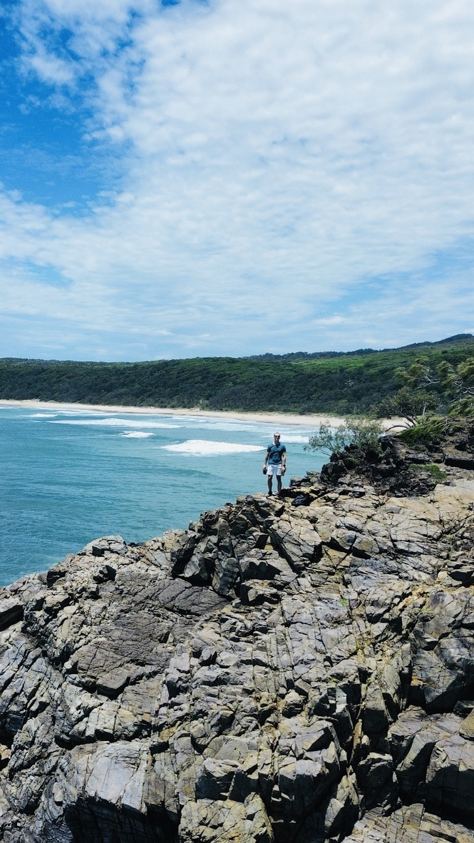 Traveler standing on rocks above a bright turquoise bay
