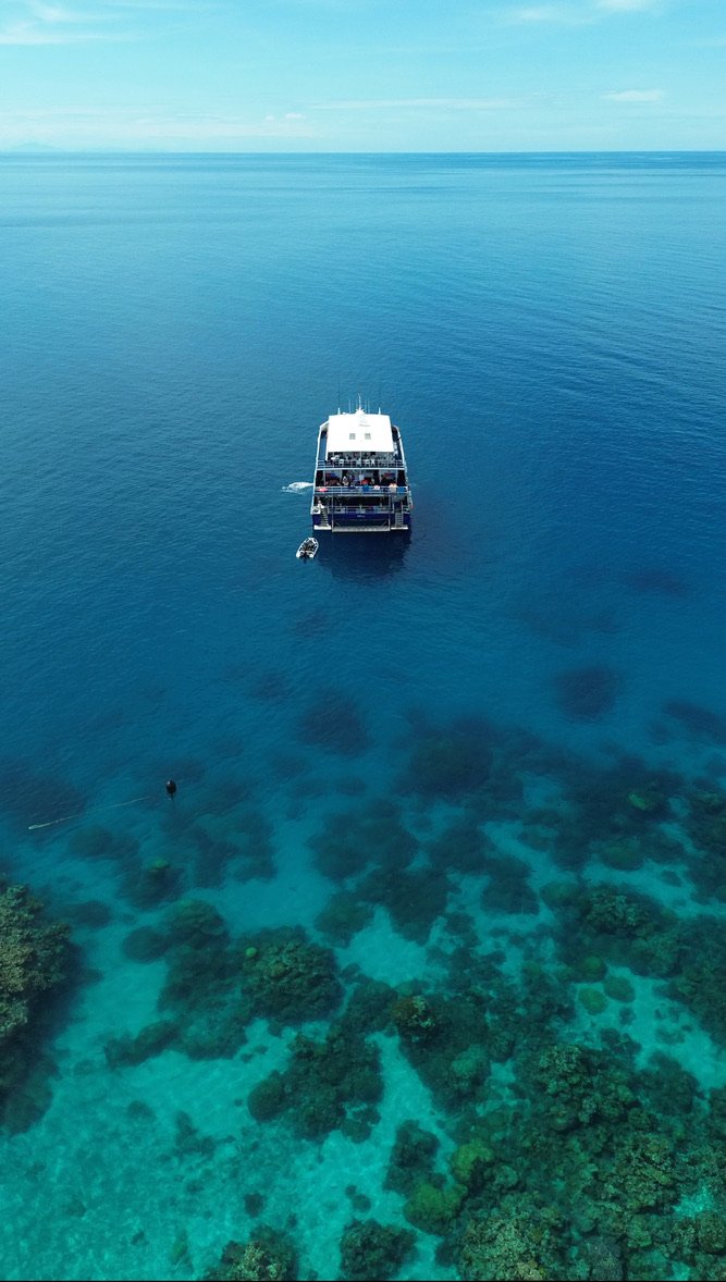 Dive boat floating above clear blue coral reef waters
