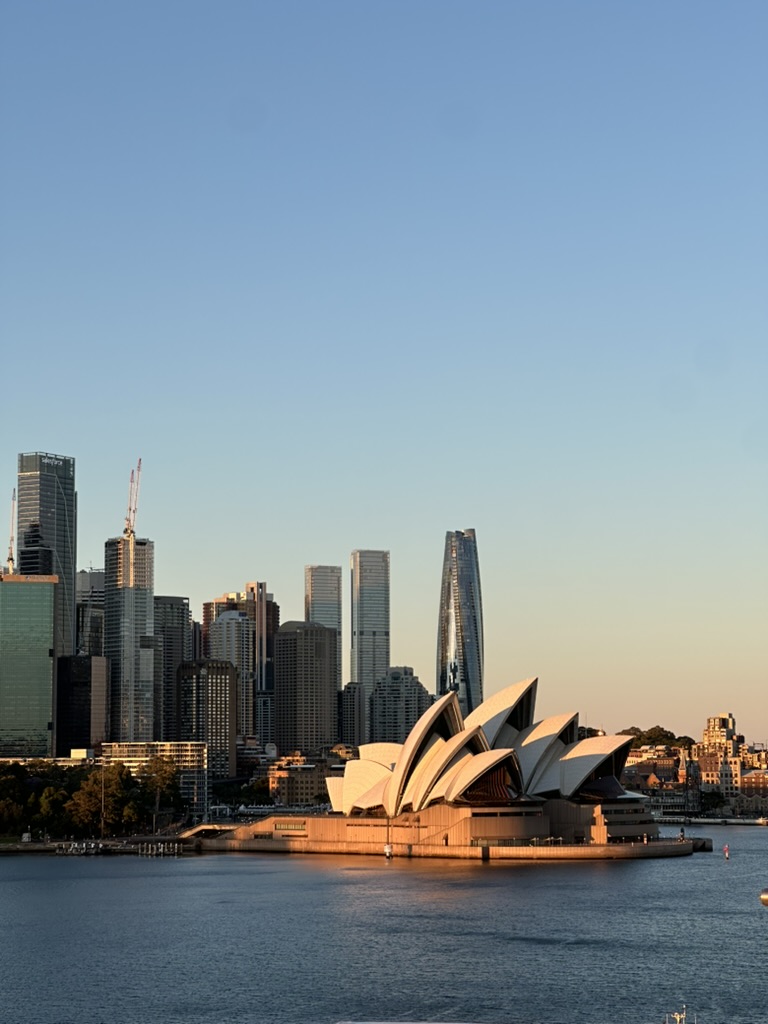 Harbourside concert hall glowing in evening light beneath the city skyline
