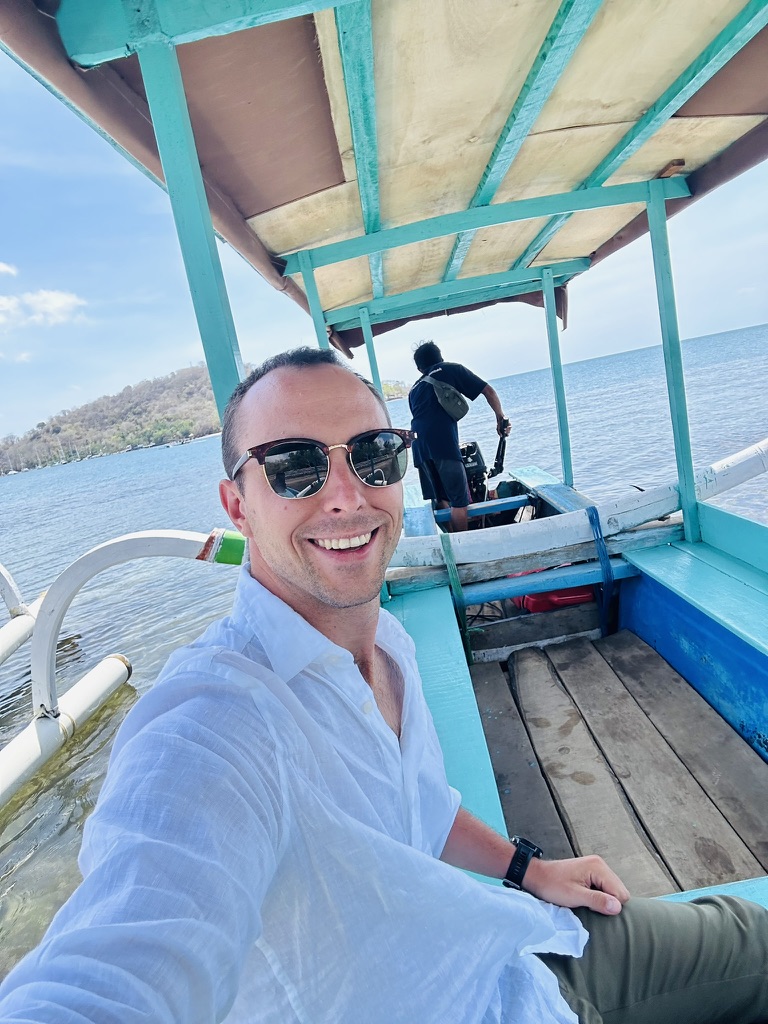 Traveler crossing between Indonesian islands in a small turquoise boat