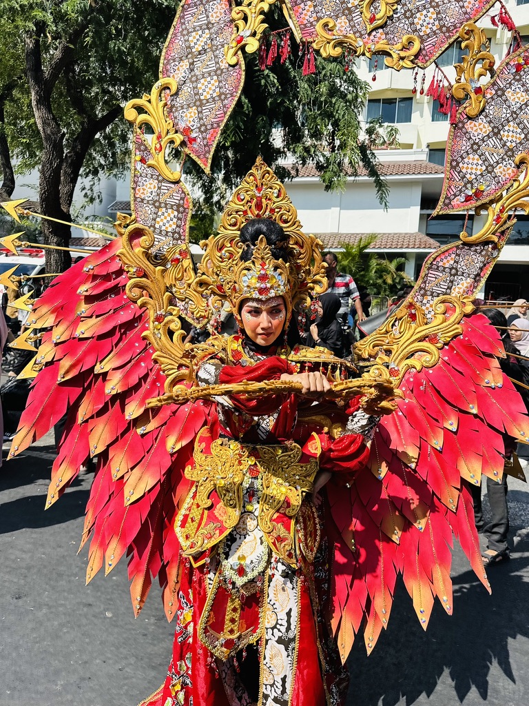 Performer in an elaborate red and gold costume at an Indonesian street festival