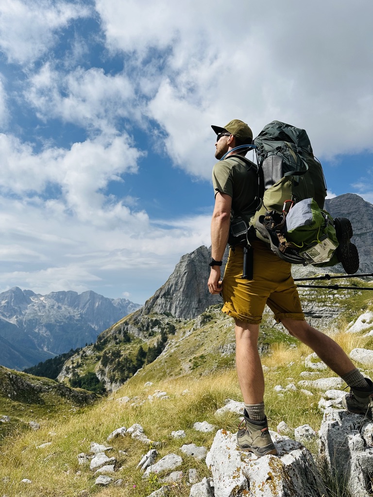 Hiker with a full pack looking out over a high border ridgeline